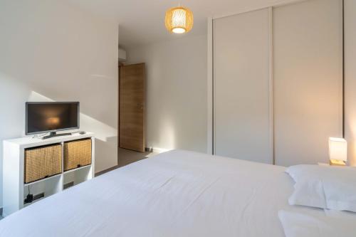 une chambre avec un lit blanc et une télévision dans l'établissement Fronte di Mare - deux pièces en bord de mer, à Propriano