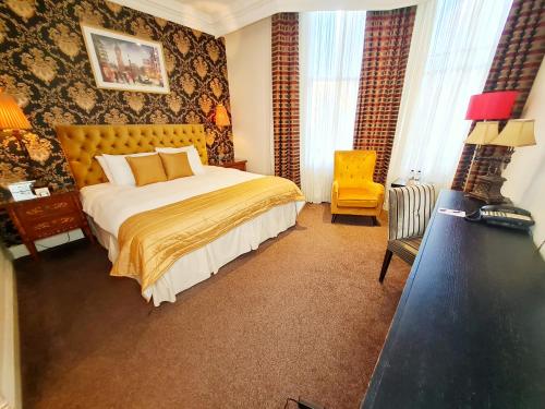 a bedroom with a bed, chair, and a television at Ashburn Hotel in London