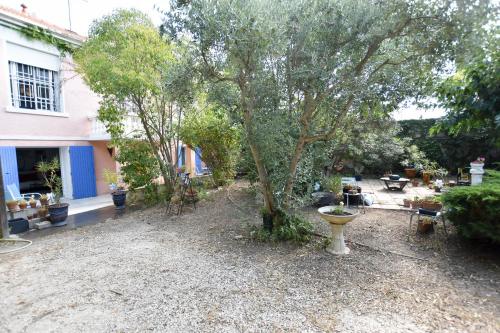 een tuin met een boom en een huis bij Moulin Rose, Parking - Jardin in Arles