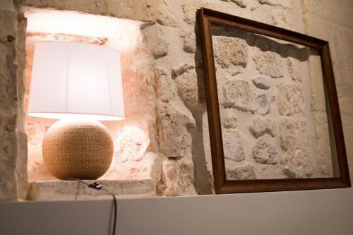 une lampe assise sur une table à côté d'un mur de pierre dans l'établissement Perchoir - Terrasse, à Arles