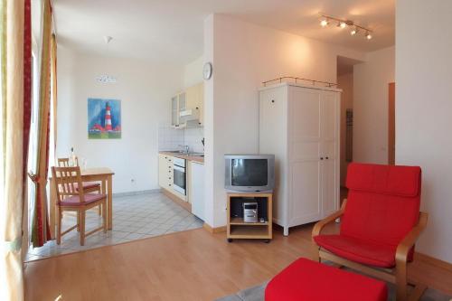 a living room with a red chair and a television at Laurin Apartment L62 in Dresden