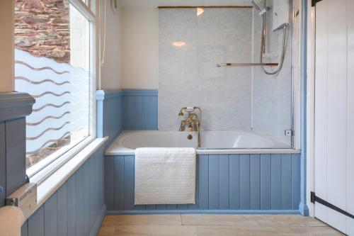 a blue bathroom with a tub and a shower at Penlee Narrows - Kingsand in Kingsand