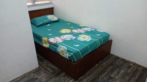 a bed with a green sheet with flowers on it at NS Homestay Private Pool in Kampong Chabir