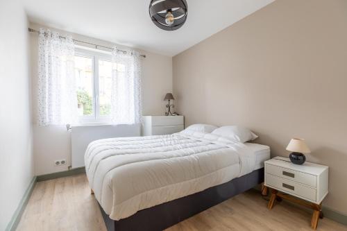 een witte slaapkamer met een groot bed en een raam bij STANDING THERMES Confort in Vichy