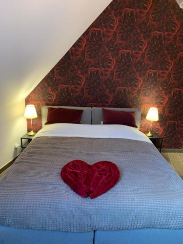 a red heart pillow sitting on top of a bed at Casa della Nonna in Zwalm