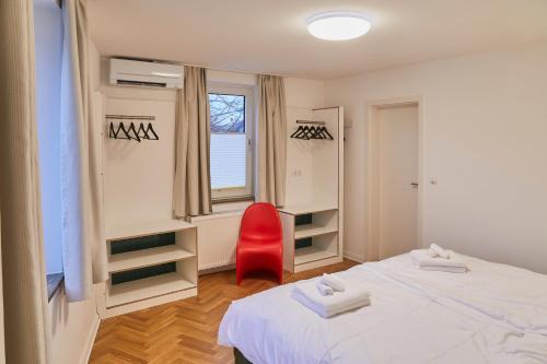 a bedroom with two beds and a red chair at Klimatisierte Wohnung mit großer Terrasse in Deidesheim