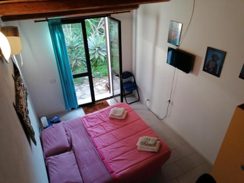 a small bedroom with a pink bed and a window at Villa Africa in Capaci