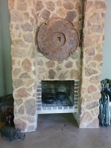 a stone fireplace with pots and pans in it at Milkwood Safari Lodge in Warmbaths