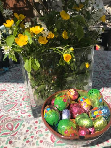 a bowl of easter eggs on a table with a vase of flowers at Le Bouyssou in Cazes-Mondenard