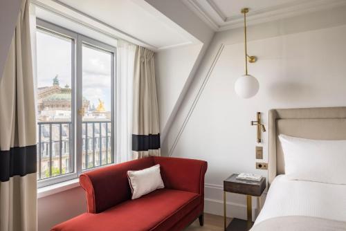 sypialnia z czerwonym krzesłem, łóżkiem i oknem w obiekcie Kimpton - St Honoré Paris, an IHG Hotel w Paryżu