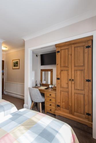 a bedroom with a desk and a bed and a cabinet at Tudor Lodge in Porthmadog