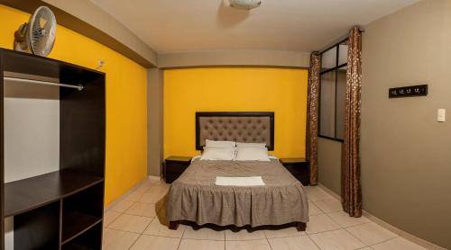 ein Schlafzimmer mit einem Bett und einer gelben Wand in der Unterkunft Hotel Residencial San Isidro in Hualmay