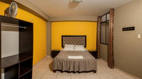 a bedroom with a bed and a yellow wall at Hotel Residencial San Isidro in Hualmay
