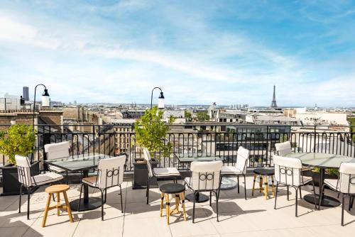 a balcony with tables and chairs and a view of the city at Kimpton - St Honoré Paris by IHG in Paris