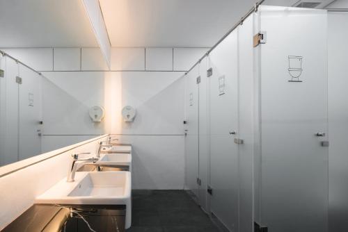 a white bathroom with two sinks and a shower at Nindya Biodistrict Hotel Bandung in Bandung