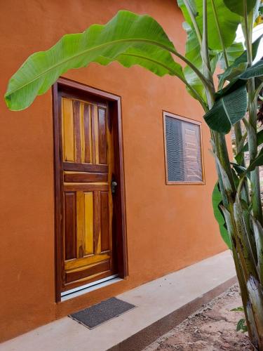 an orange building with a door and a plant at Aconchego na Chapada in Lençóis