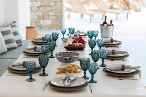 a table with blue glasses and plates on it at Mesmerizing 5bed Villa with Pool in Kanalia in Agios Ioannis Mykonos