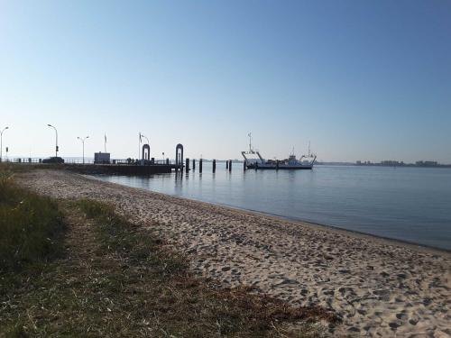 a beach with a dock and a boat in the water at Ruegen Fewo 168 in Zudar