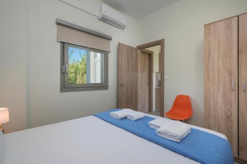 um quarto com uma cama e uma cadeira laranja em SEA BREEZE APARTMENTS em Kolymvari