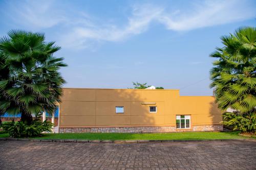 a yellow building with palm trees in front of it at Fleur Guest House in Kigali
