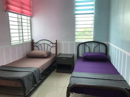 2 letti in una camera con pareti rosa e viola di Me'Na Homestay, Sepang a Kampong Salak Tinggi