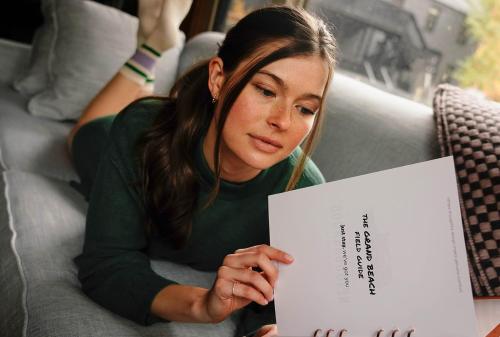 a woman laying on a couch holding a piece of paper at The Neighborhood Hotel Grand Beach in New Buffalo