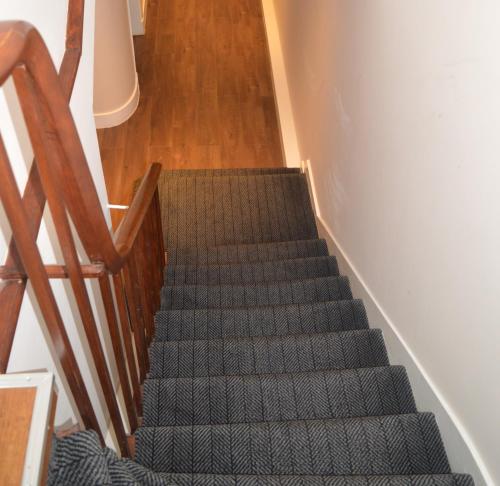 a staircase with a green carpet and a wooden stair case at Jewel Guest House in Aberdeen