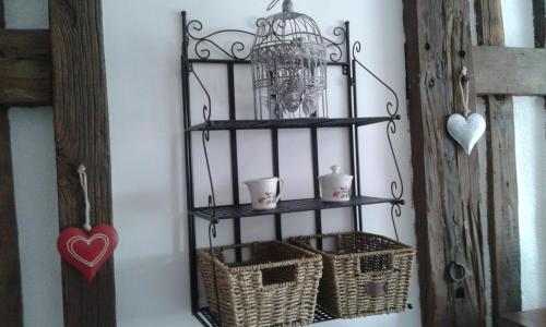 a shelf with baskets and a bird cage on a wall at La petite maison dans la prairie in Notre-Dame-du-Touchet