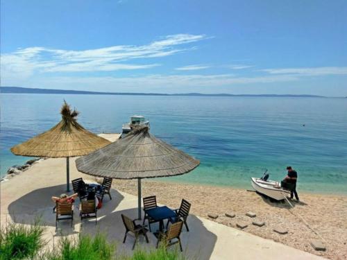 un gruppo di sedie e ombrelloni su una spiaggia con barca di Mintos Luxury Resort a Podstrana
