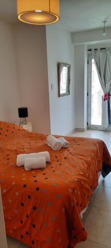1 dormitorio con 1 cama grande de color naranja y toallas. en Paula departamento en Salta