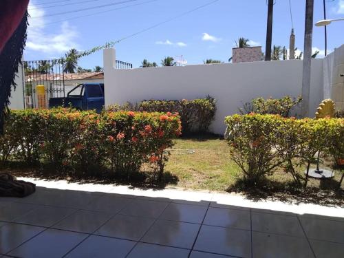 a garden with flowers and a white fence at Casa Milagres in São Miguel dos Milagres