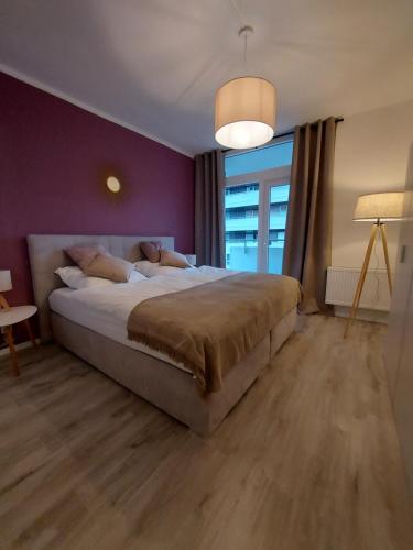1 dormitorio con 1 cama grande y pared morada en Berg-Blick-Fewo, en Bad Harzburg