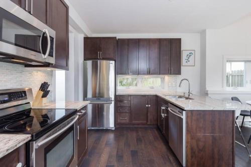 a kitchen with wooden cabinets and stainless steel appliances at West Coast Luxury Living in Vancouver