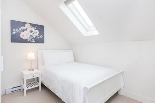 a white bedroom with a bed and a night stand at West Coast Luxury Living in Vancouver