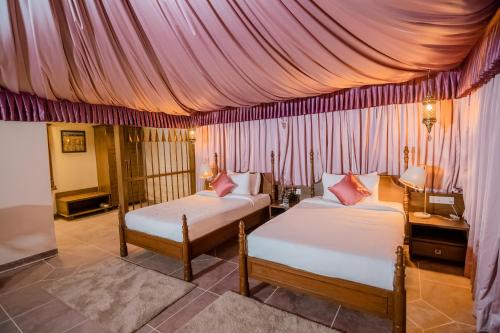 a bedroom with two beds and a canopy at WelcomHeritage Tadoba Vanya Villas Resort & Spa in Kolāra