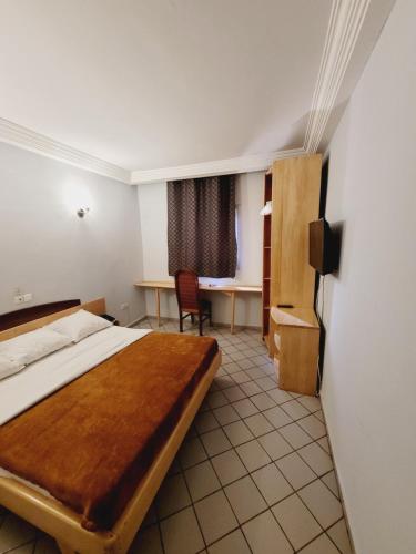 a hotel room with a bed and a desk at Hôtel Altitel in Bafoussam