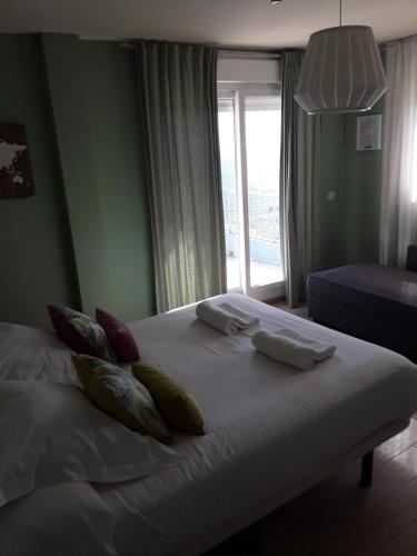 a bedroom with a bed with pillows and a window at Punta Carnero Hostal in Algeciras