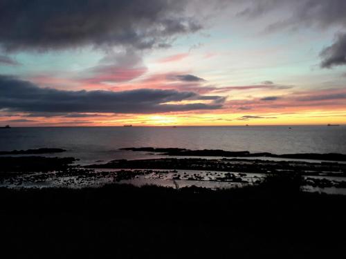a sunset over the ocean with rocks in the water at Punta Carnero Hostal in Algeciras