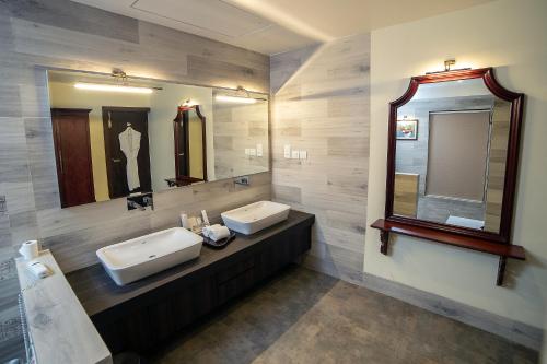 a bathroom with two sinks and two mirrors at WelcomHeritage Tadoba Vanya Villas Resort & Spa in Kolāra