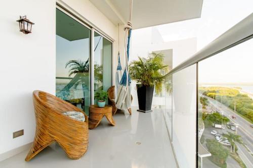 a room with chairs and a balcony with windows at Hermoso apartamento con todas las comodidades acceso directo a la playa ubicado en el edificio Morros Epic in Cartagena de Indias