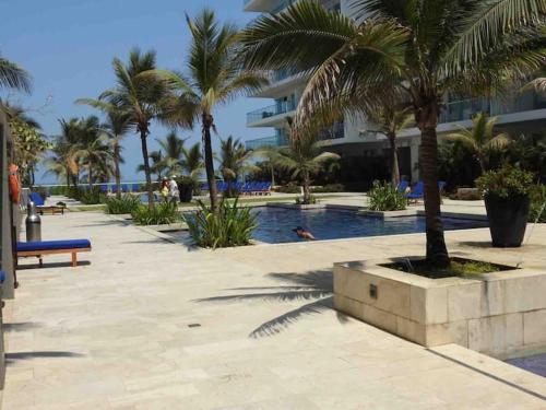 a swimming pool with palm trees and a building at Hermoso apartamento con todas las comodidades acceso directo a la playa ubicado en el edificio Morros Epic in Cartagena de Indias