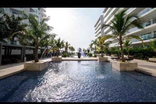 a swimming pool with palm trees in front of a building at Hermoso apartamento con todas las comodidades acceso directo a la playa ubicado en el edificio Morros Epic in Cartagena de Indias