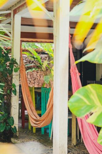a hammock on the porch of a house with plants at Tropical Hostel in Pipa
