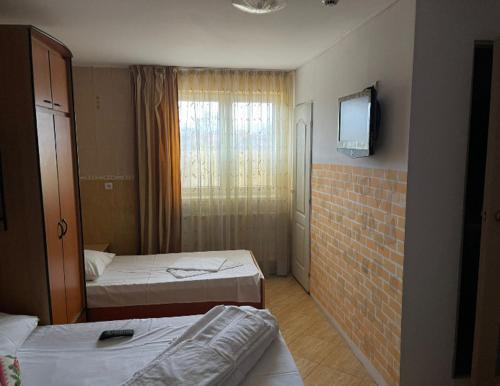 a room with two beds and a tv on a wall at Cazare ieftina in Piatra Neamţ