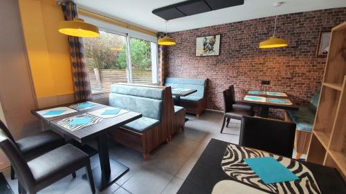 une salle à manger avec des tables et des chaises et un mur en briques dans l'établissement Hôtel Les Pieux En Cotentin, aux Pieux