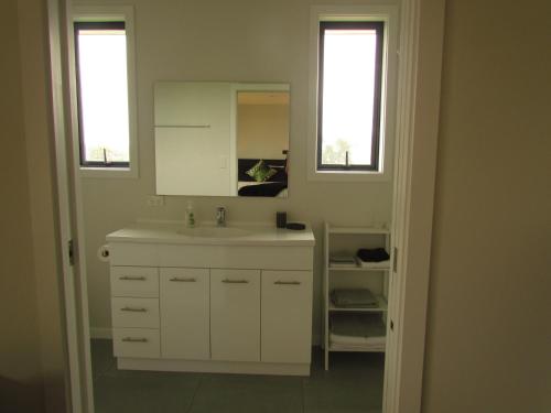 a white bathroom with a sink and two windows at The Bunkhouse in Waiau