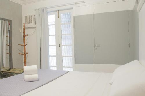 um quarto branco com uma cama e uma janela em Studio Centro de Búzios em Búzios