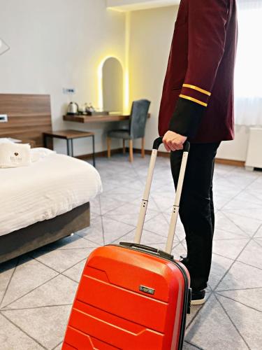 a person pulling a red suitcase in a hotel room at Bushi Resort & SPA in Skopje