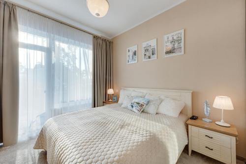 a bedroom with a white bed and a large window at Turaidas Kvartals Four Seasons Luxury Apartment in Jūrmala