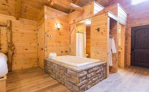a bathroom with a stone tub in a wooden wall at Lofty Willows Treehouse by Amish Country Lodging in Millersburg